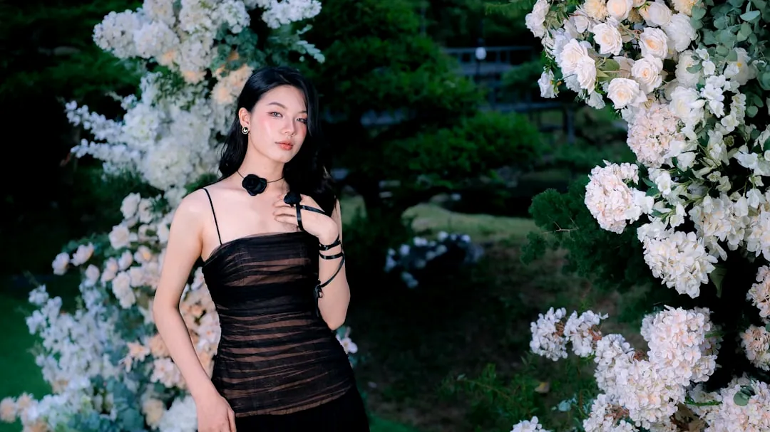 Young woman in black dress with floral arch