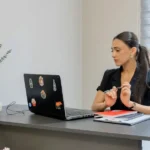 Woman working on a laptop at a desk.