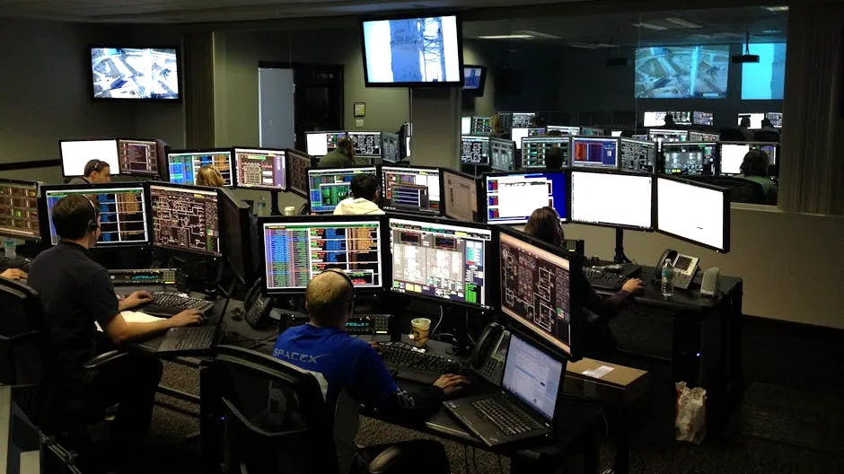 A bustling control room with people working on multiple computer monitors.