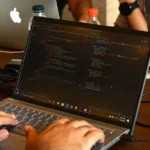 a man using a laptop computer on a wooden table