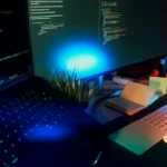 Computer screens displaying code with neon lighting.