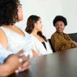 five people sitting at table and talking