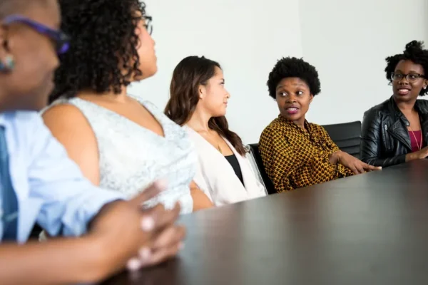 five people sitting at table and talking