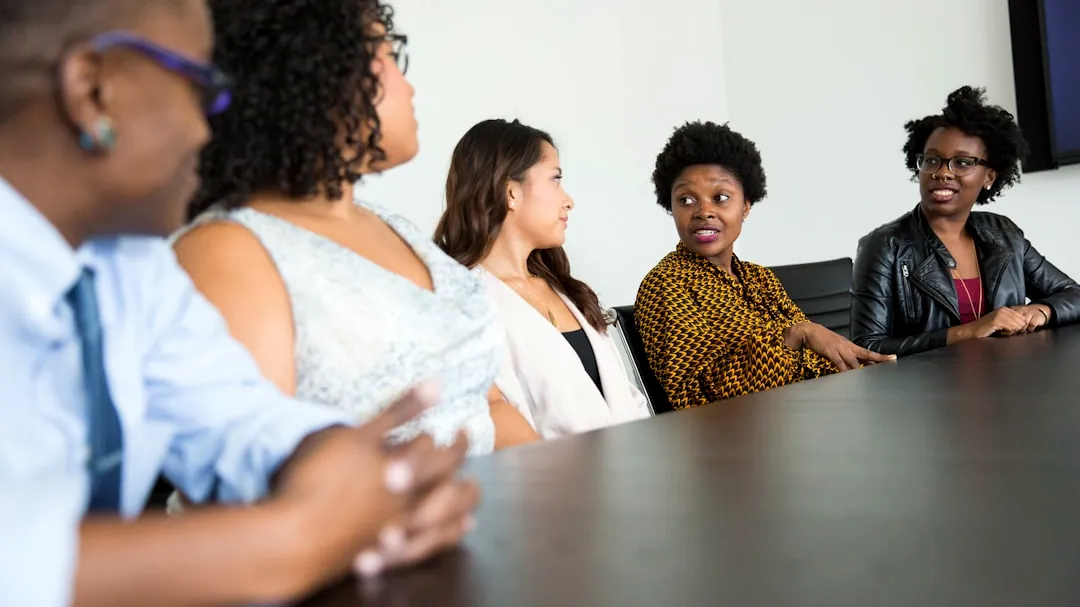 five people sitting at table and talking