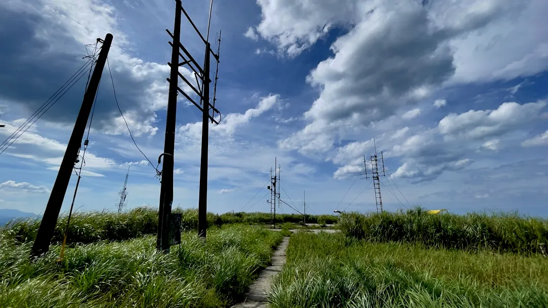 gray wooden fence on green grass field under blue sky and white clouds during daytime