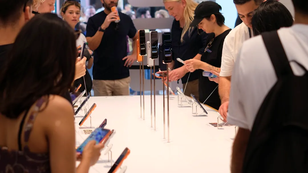 People examining smartphones displayed on a table.
