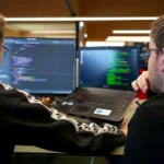 two men sitting in front of a laptop computer