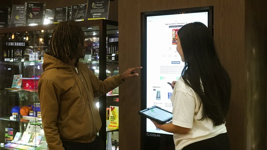 Two people interact with a digital display screen.