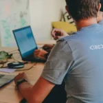 Two people working on laptops at a table.