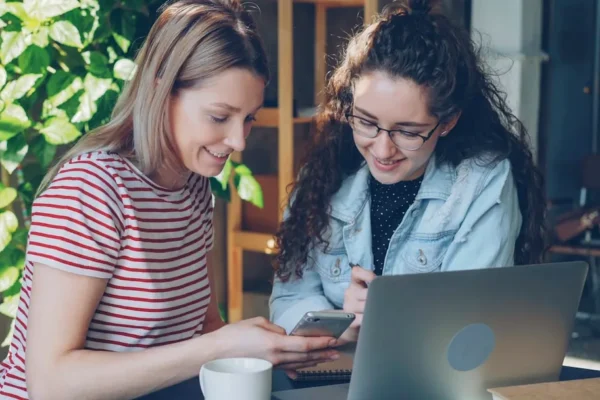 Two women collaborate on a laptop.