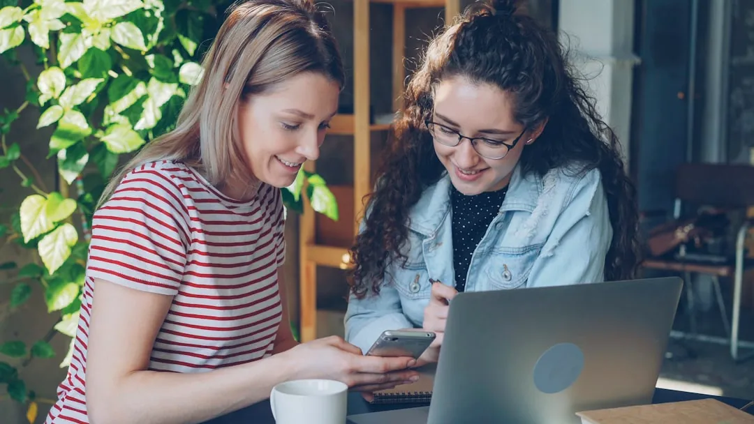 Two women collaborate on a laptop.
