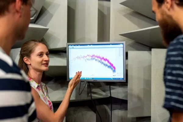 woman in white and red floral sleeveless top standing beside black flat screen tv