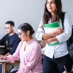 woman carrying white and green textbook